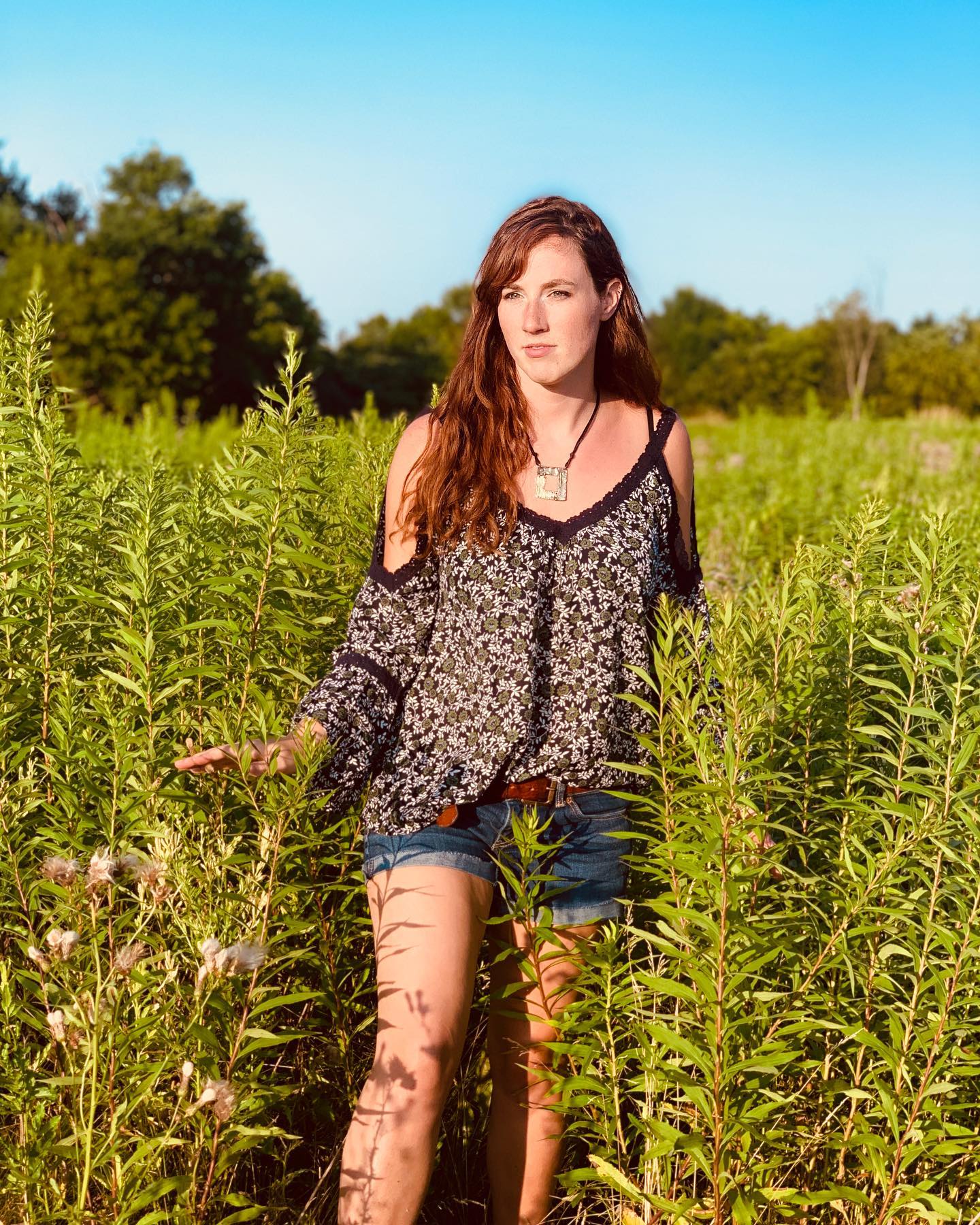 A woman is standing in a field of tall grass.