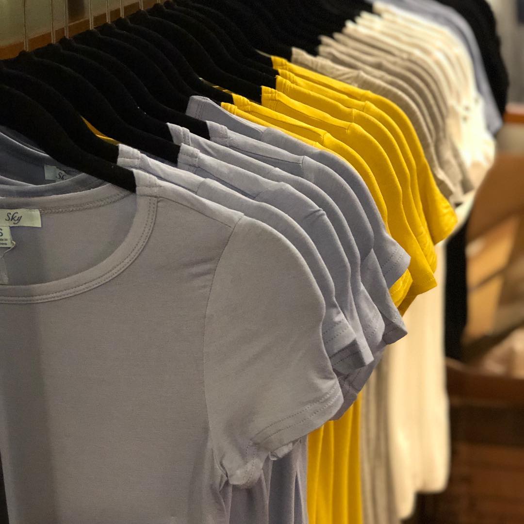 A row of t-shirts are hanging on a rack in a store