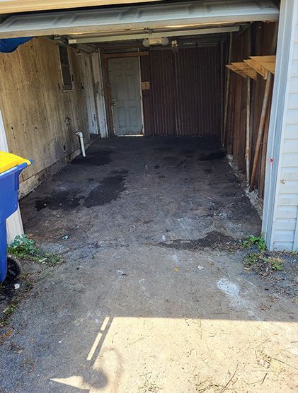An empty garage with a trash can in front of it.