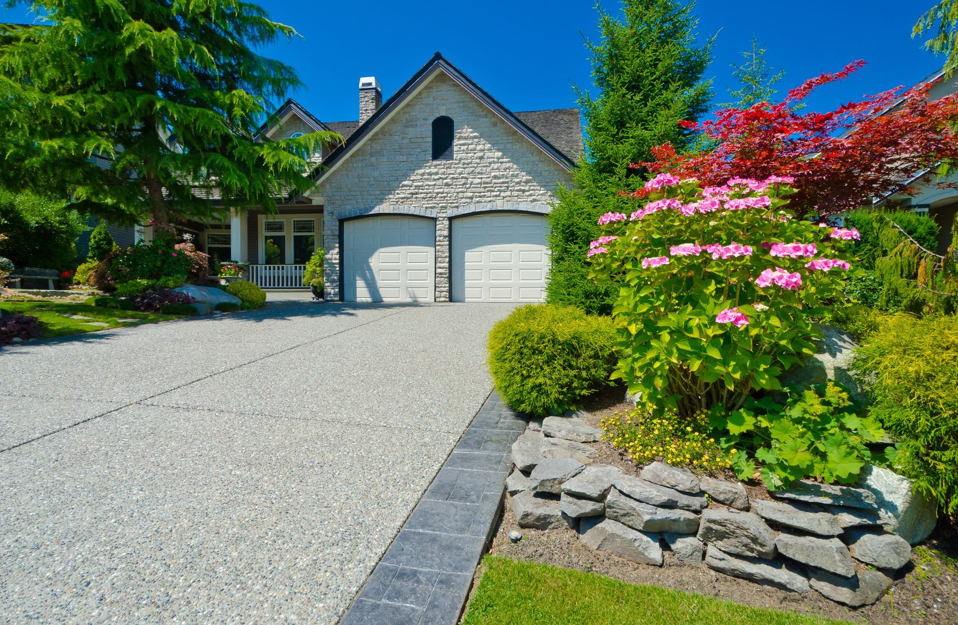 A large house with two garages and a driveway in front of it.