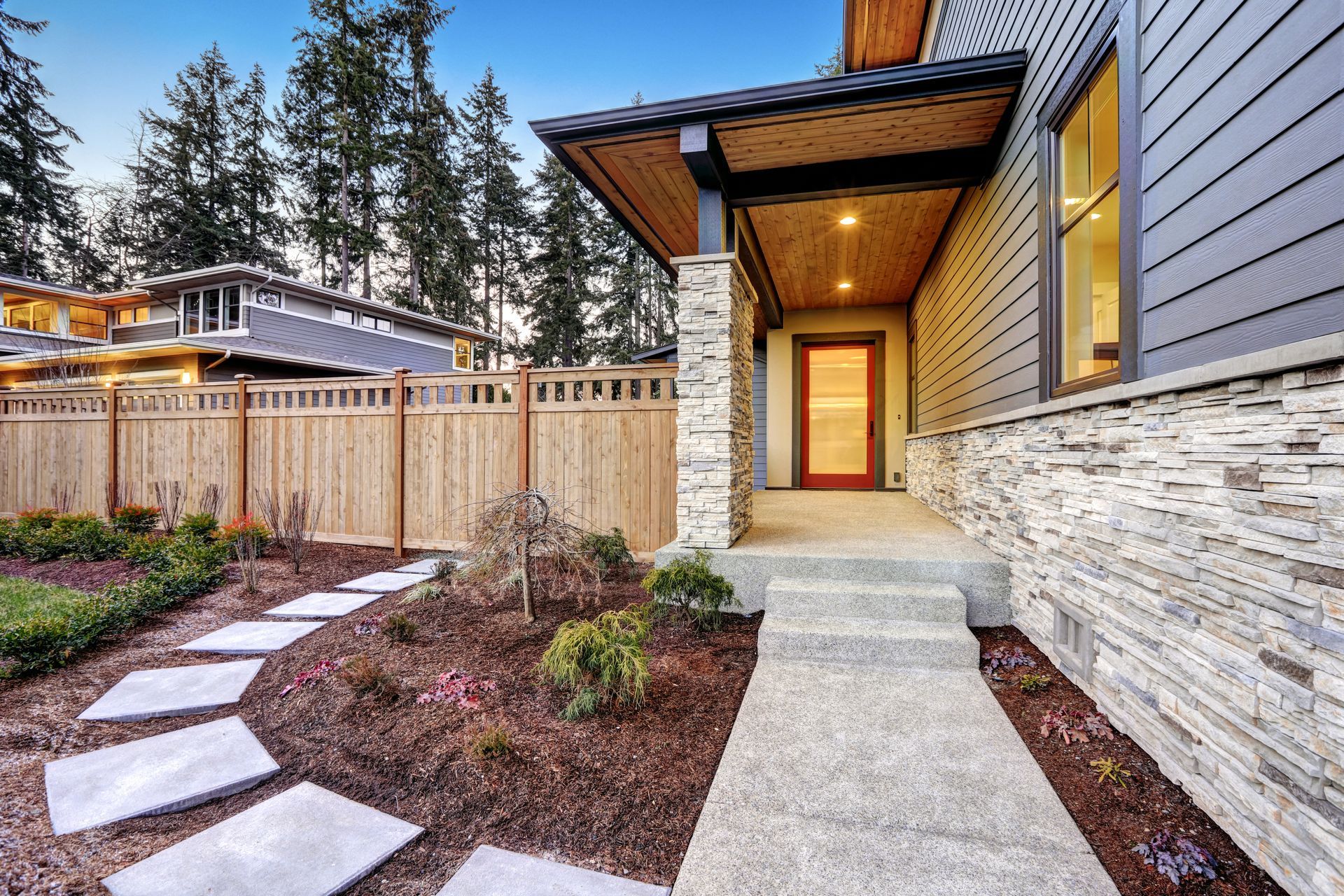 A house with a stone walkway leading to the front door and a wooden fence.