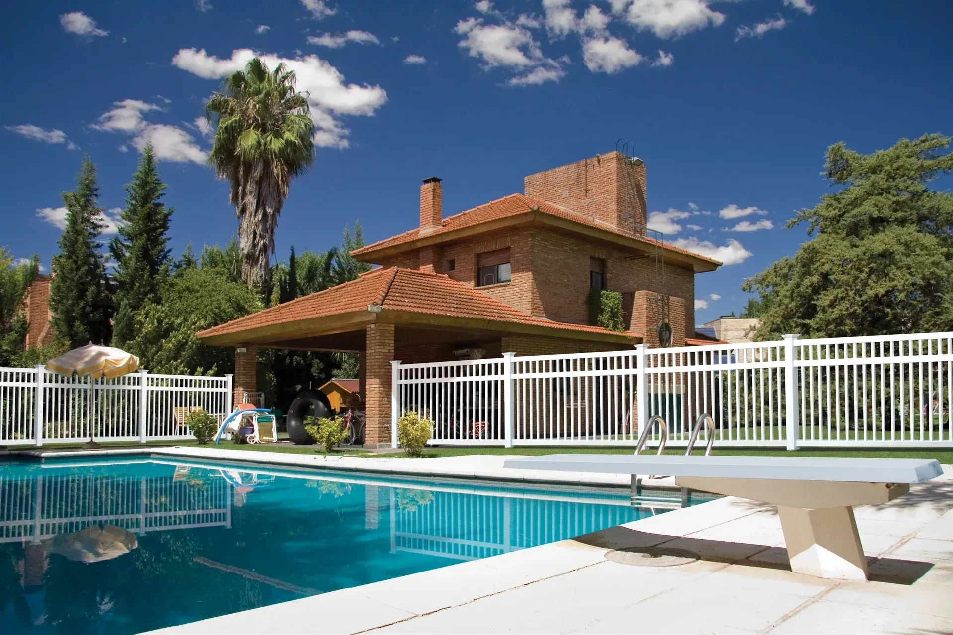 A luxury villa with a tiled roof, open living area, and swimming pool set in a tropical, sunlit landscape.