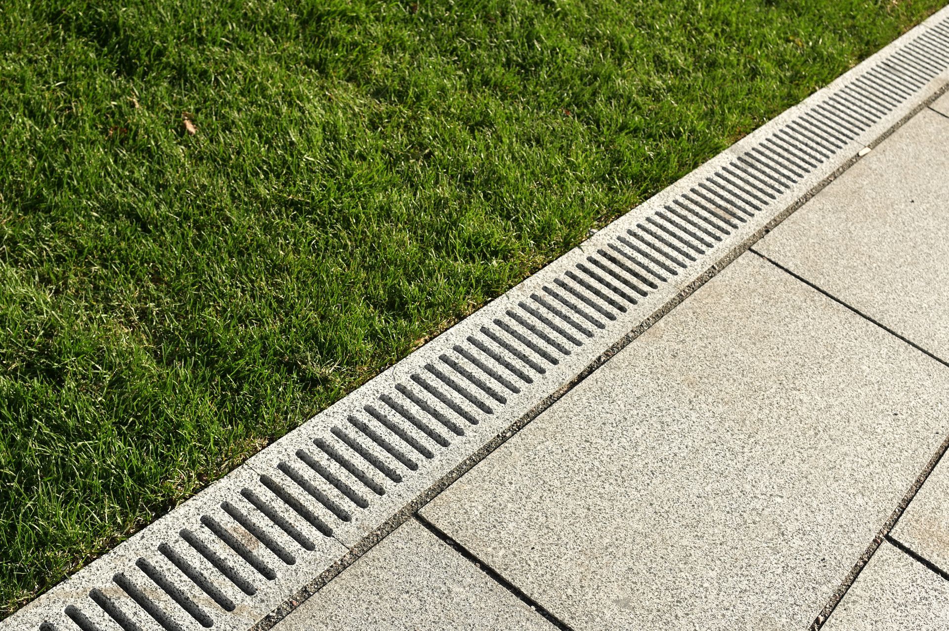 Elite Outdoor Living Solutions is installing a surface drain along a sidewalk in Crown Heights, OKC.