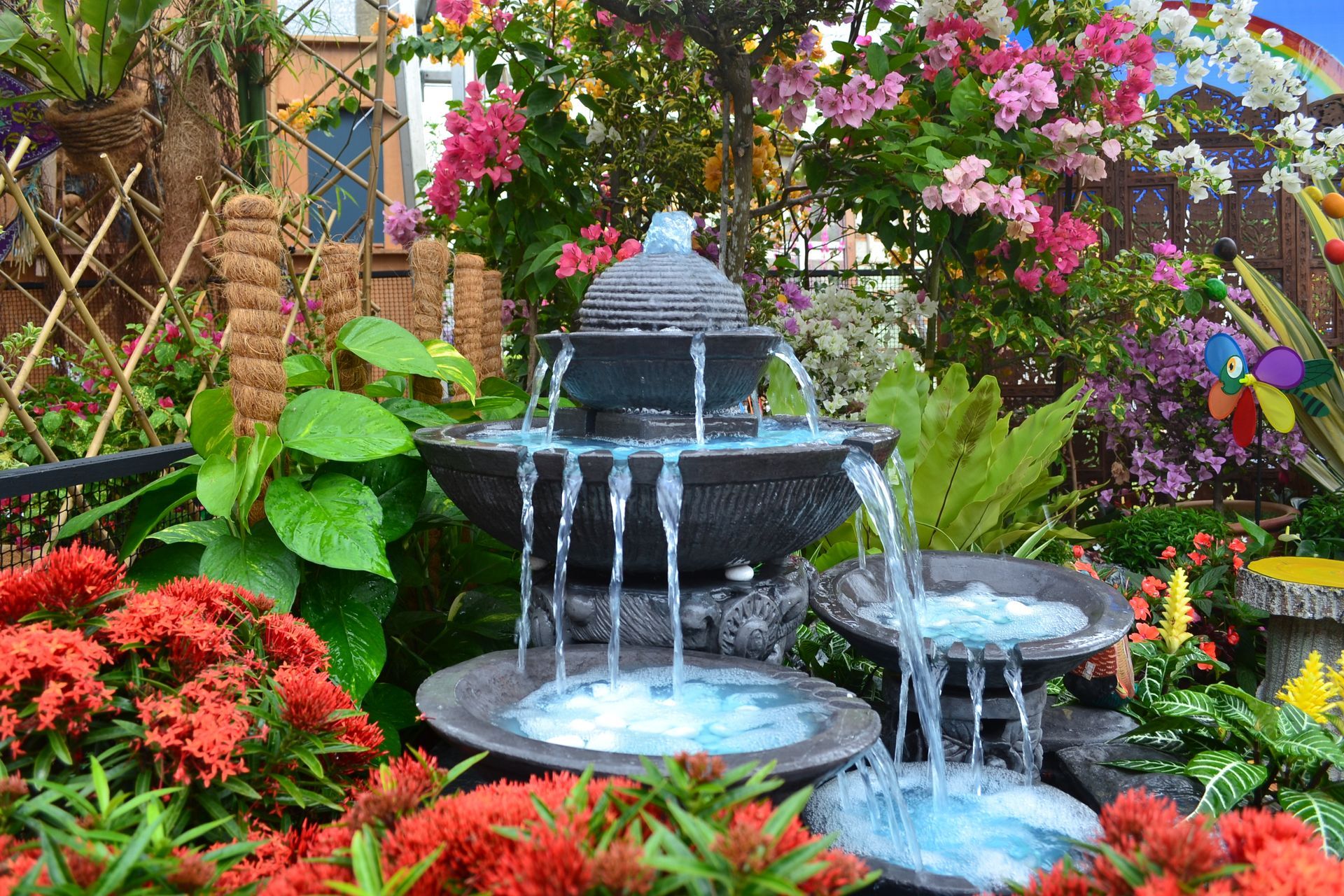A water fountain in a garden surrounded by flowers and plants.