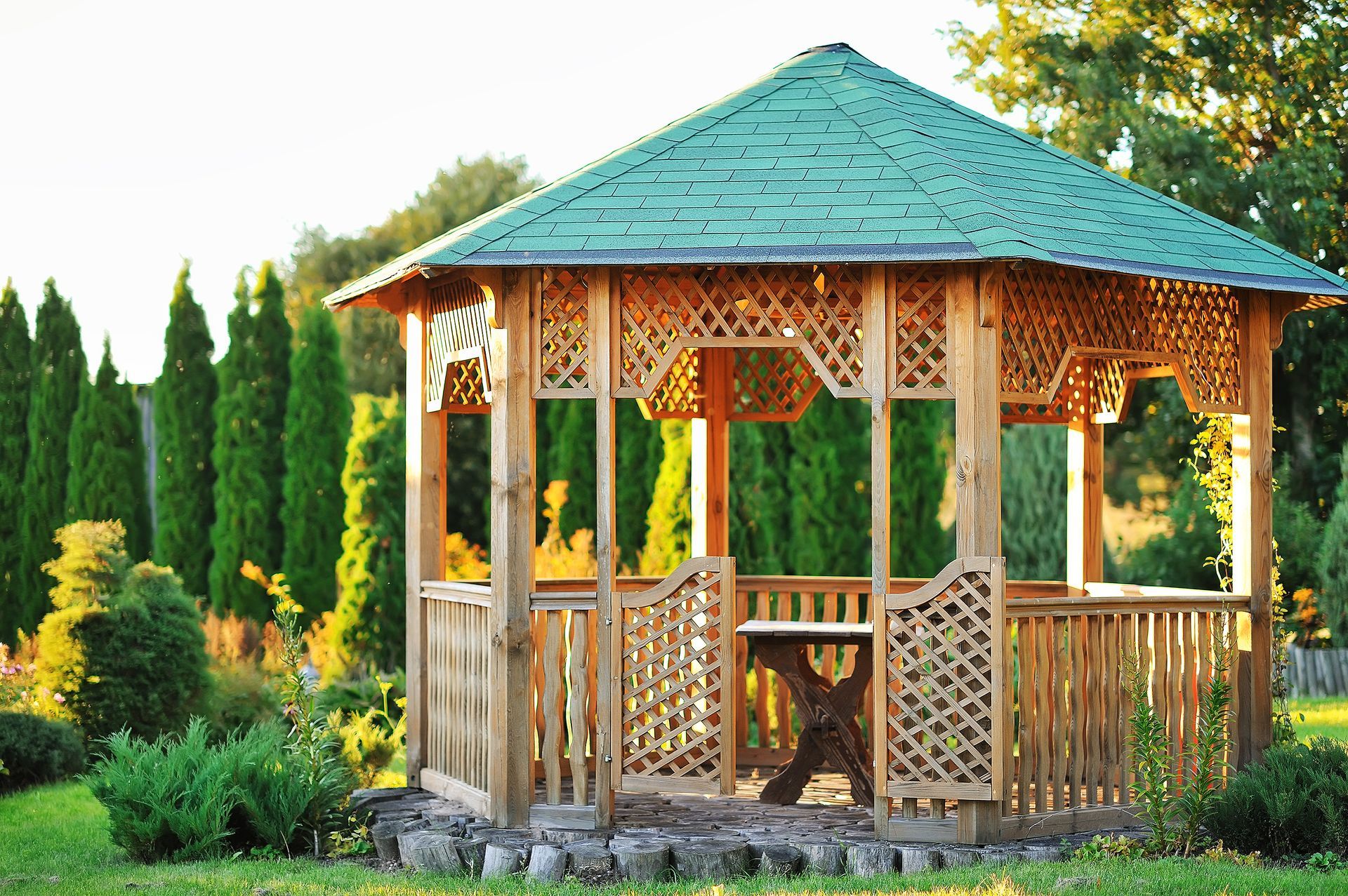 A wooden gazebo with a green roof in a garden