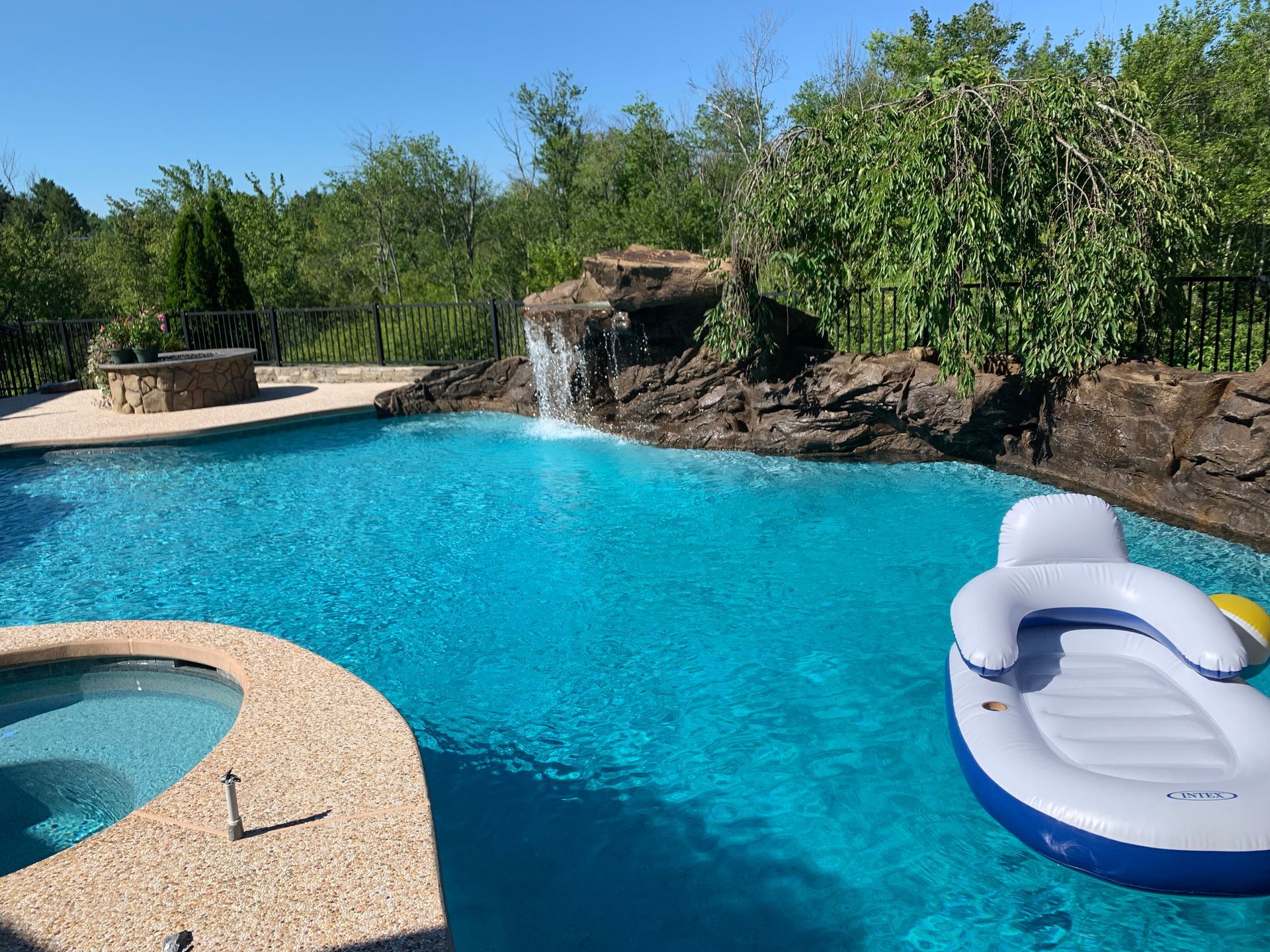 A large swimming pool with a waterfall and a raft in it
