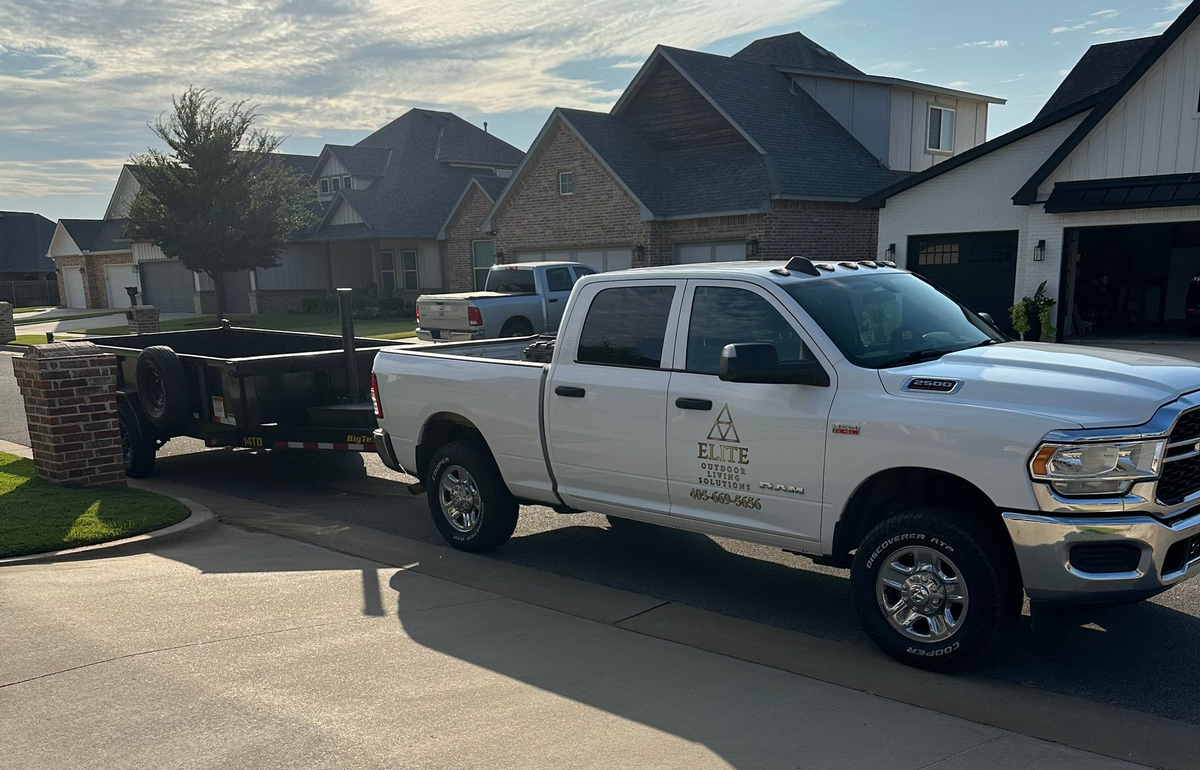 White pickup truck towing a trailer on a suburban street in front of houses