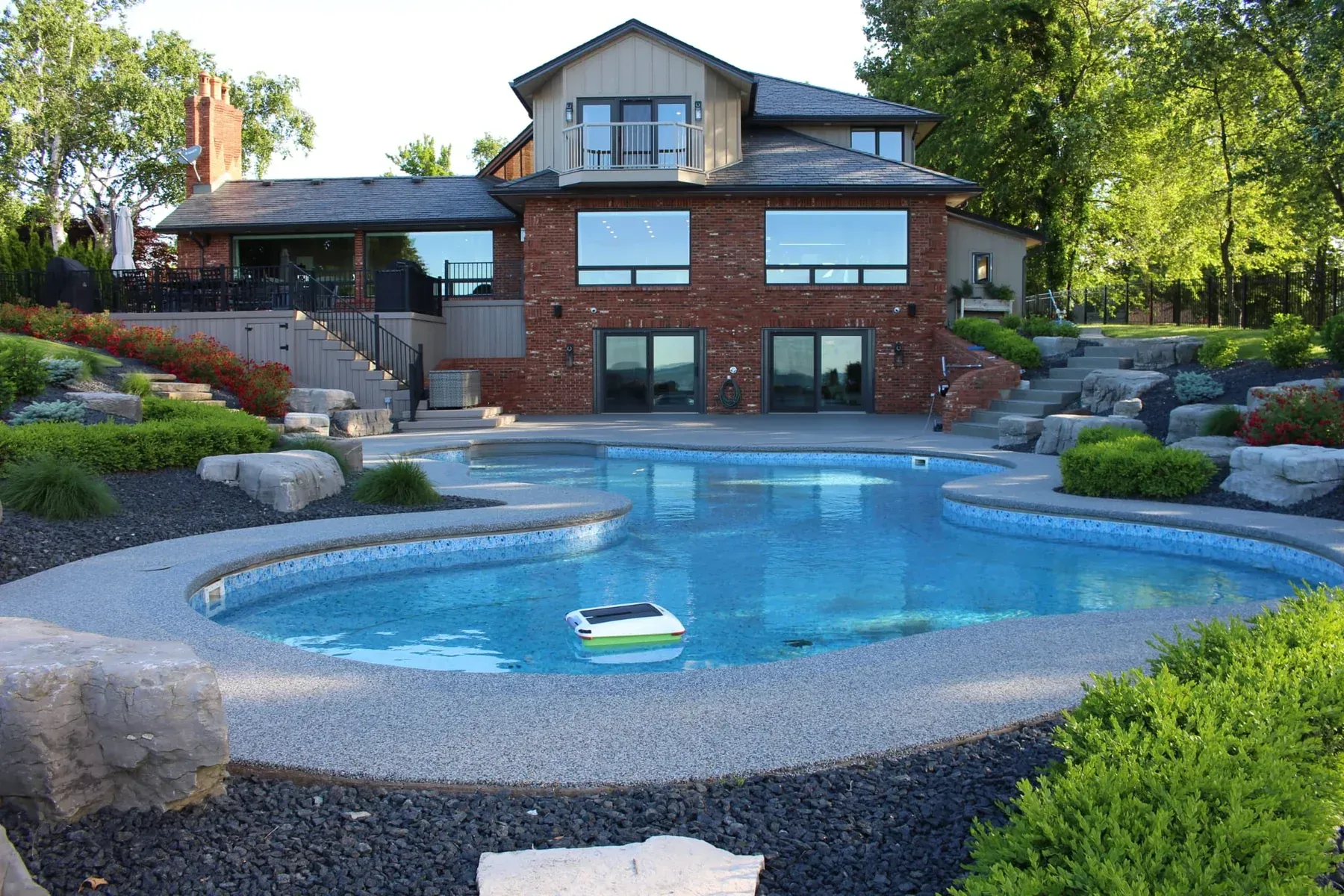Luxurious house with brick facade and large pool surrounded by landscaping.