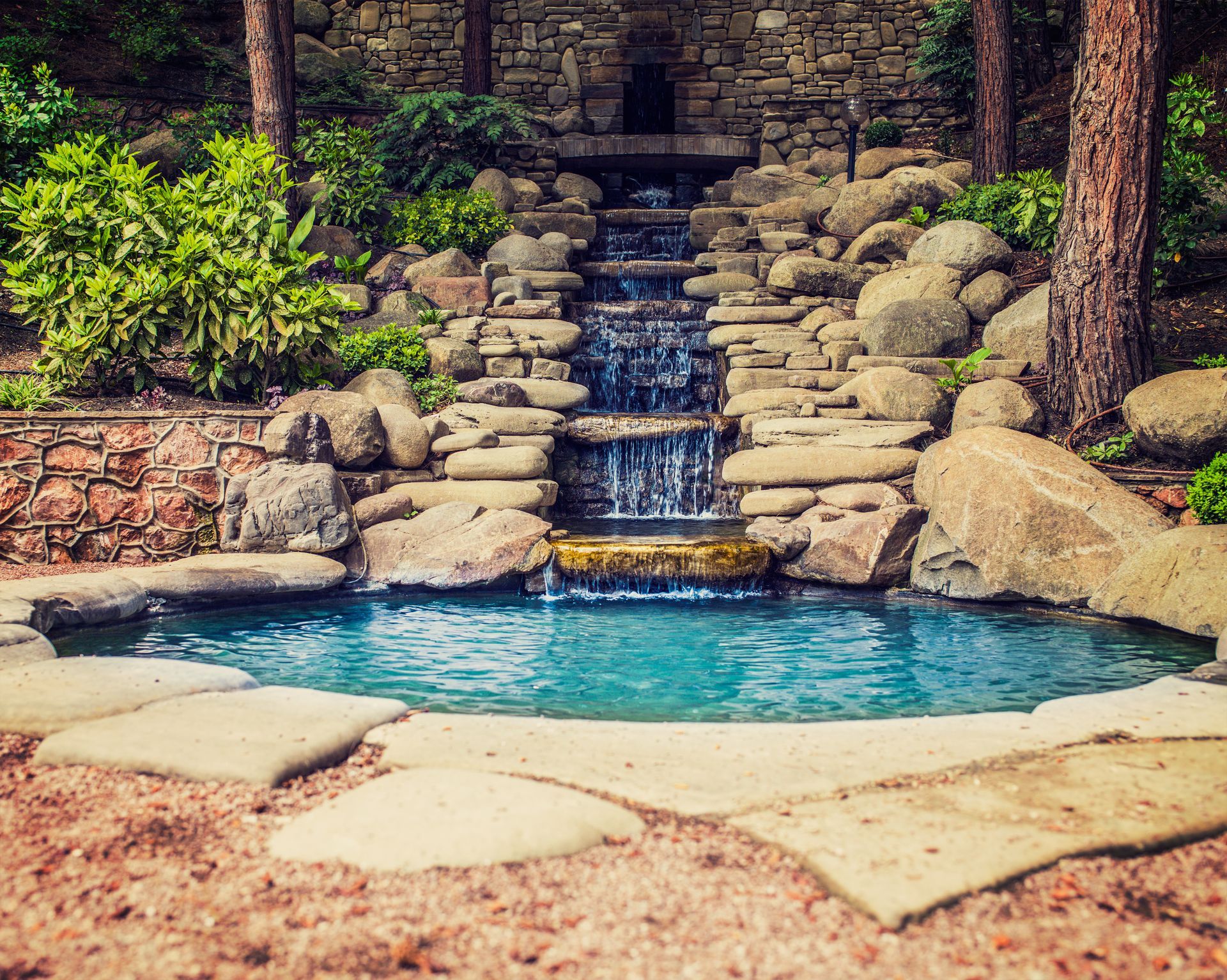 There is a waterfall in the middle of a pool surrounded by rocks.