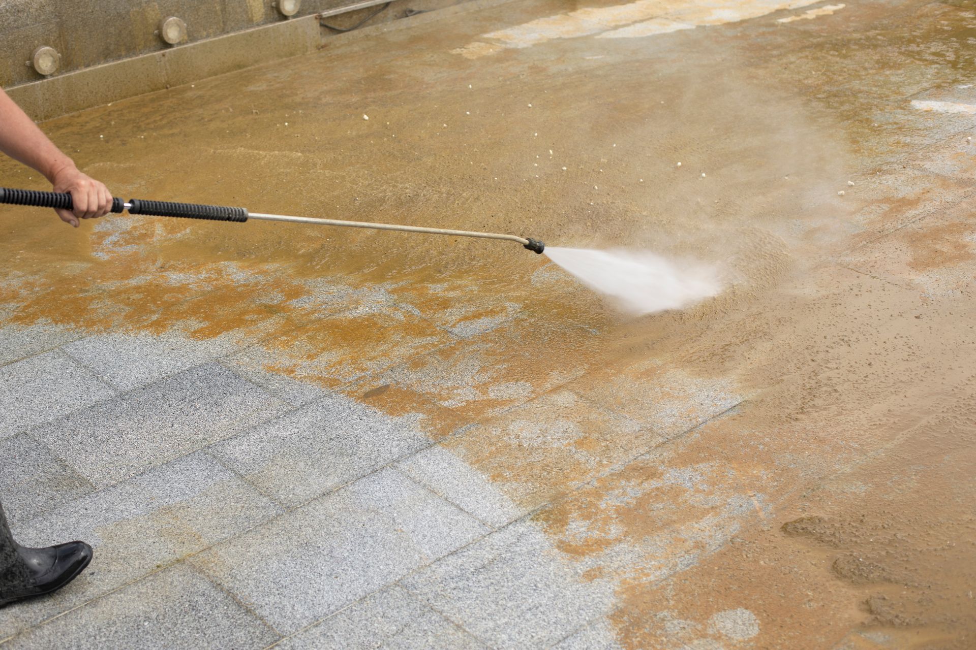 Elite Outdoor Living Solutions is pressure washing a filthy concrete driveway surface in Lakehurst, OKC.