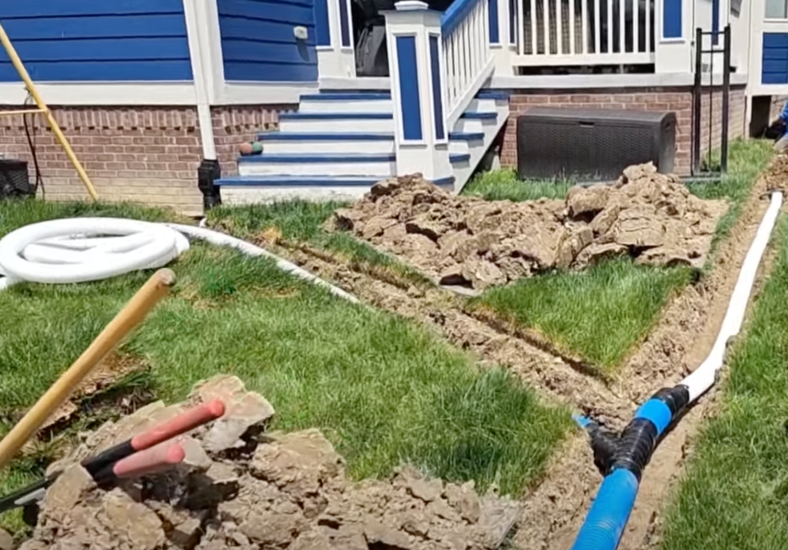 Elite Outdoor Living Solutions installing a residential drainage system in front of a house in Oklahoma City.