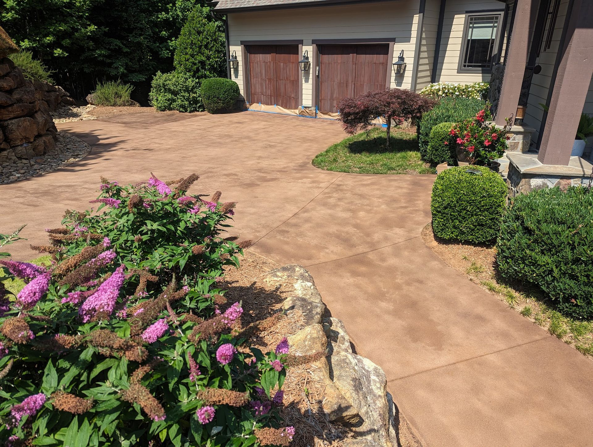 Elite Outdoor Living Solutions stained a residential driveway with flower landscaping in Oklahoma City.