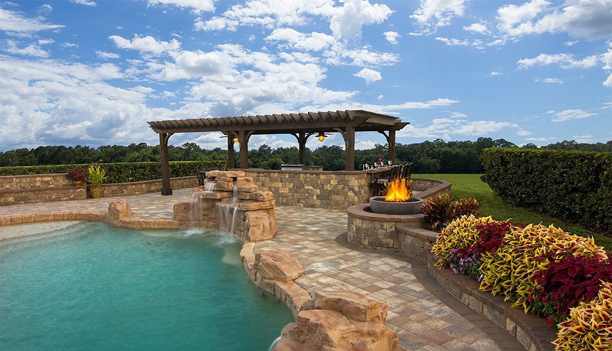 Elite Outdoor Living Solutions built a pool area with a waterfall, landscaping, and fire pit in Piedmont, OK.