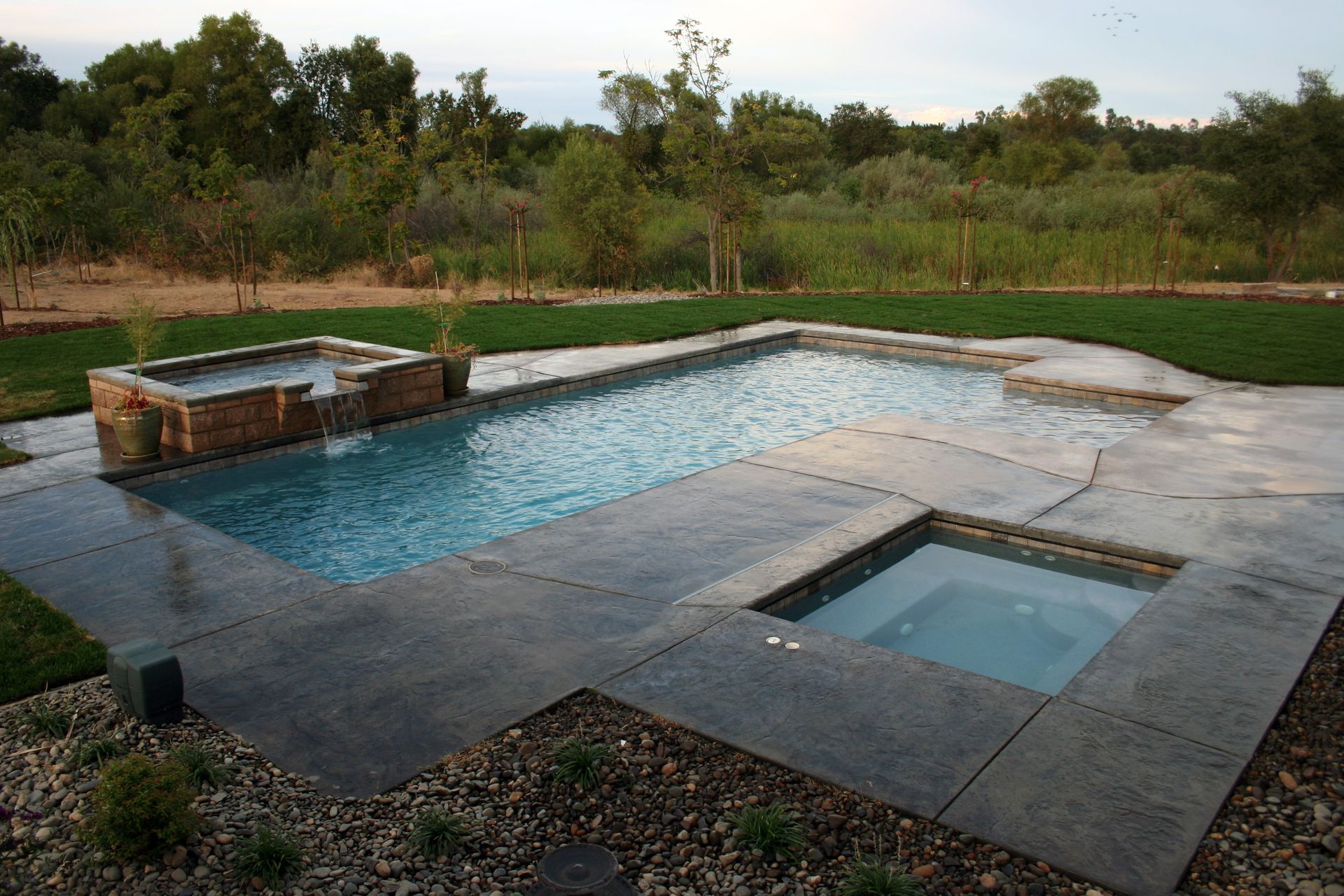 Elite Outdoor Living Solutions is installing a modern design custom pool deck with a hot tub in Yukon, OK.