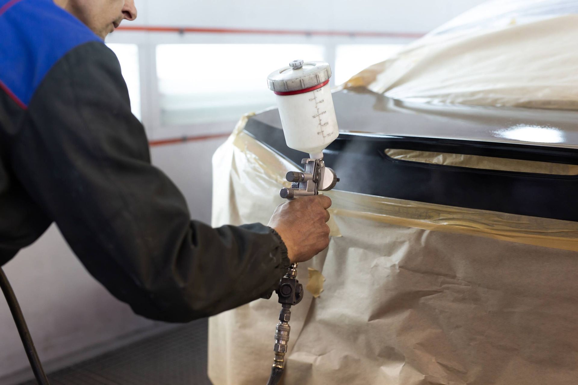 A man is spray painting a car in a garage.