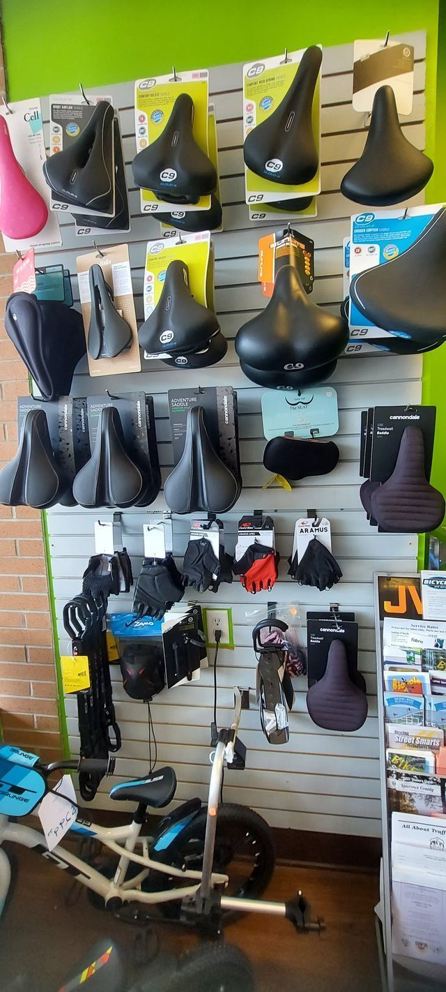 A bicycle is parked in front of a wall filled with bicycle seats.