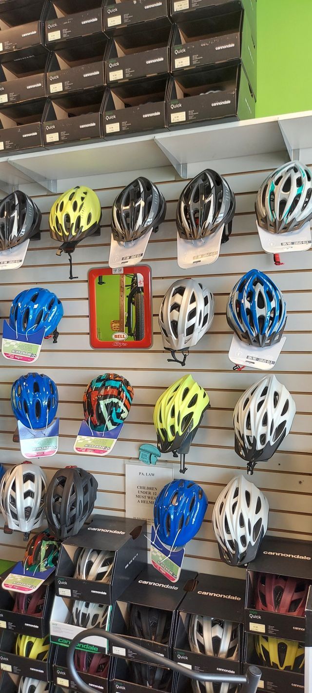 A wall filled with lots of bicycle helmets in a store.