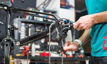 A man is working on a bicycle in a workshop.