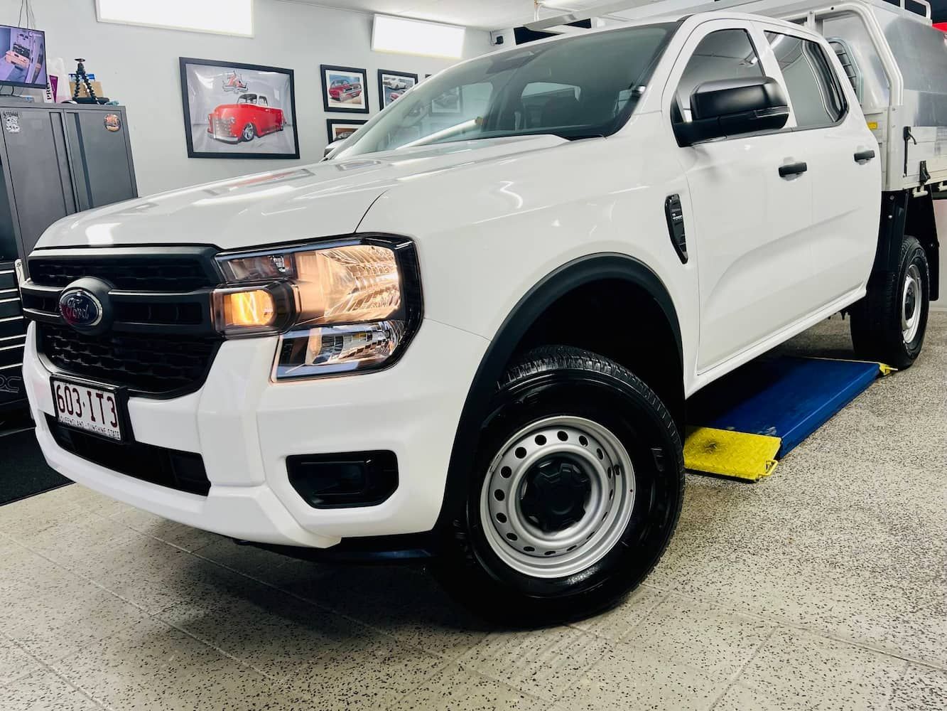 A White Truck is Parked on a Lift in a Garage — Straightline Detailing Cairns in Bungalow, QLD