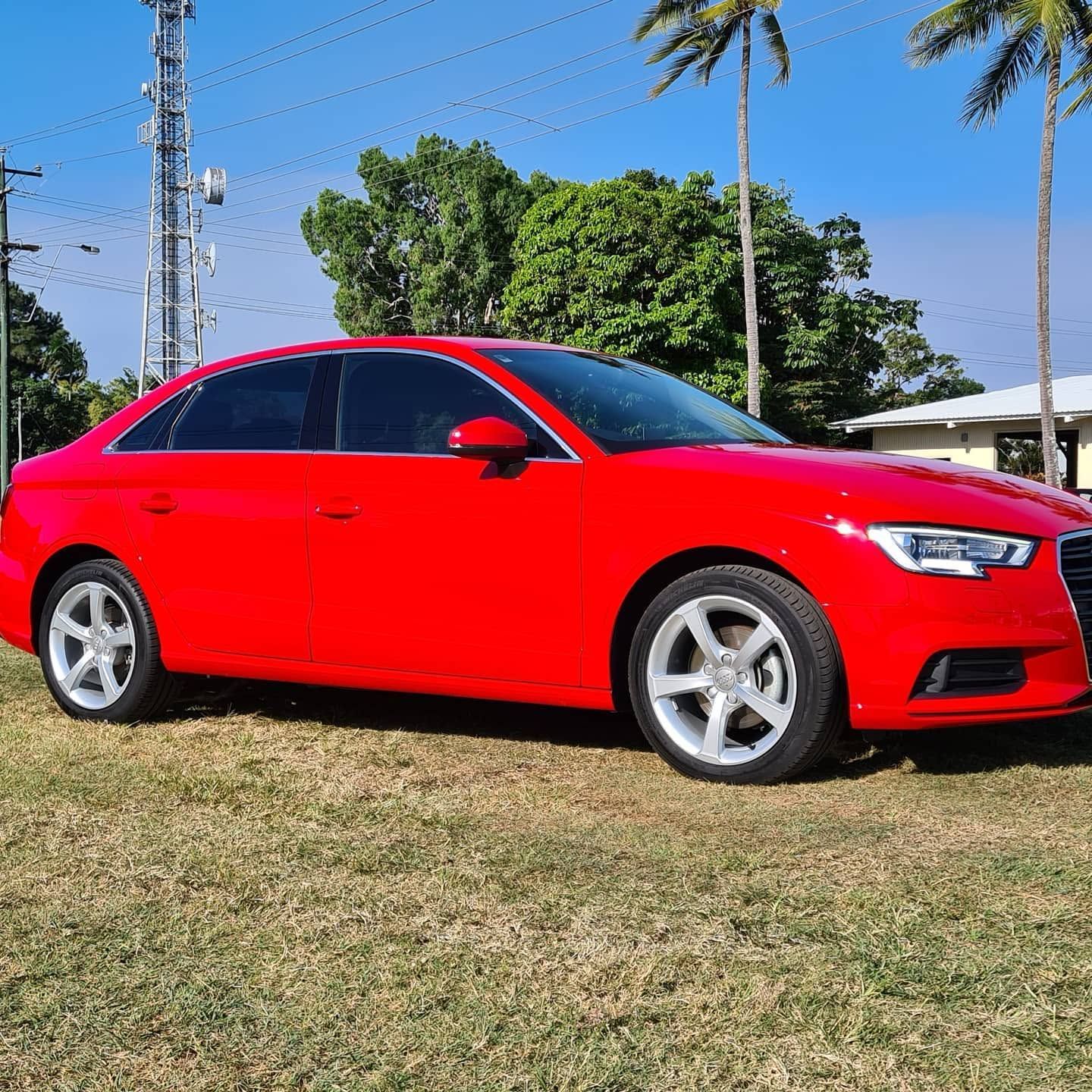 Red Sedan Parked on Grass Under a Clear Blue Sky — Straightline Detailing Cairns in Bungalow, QLD