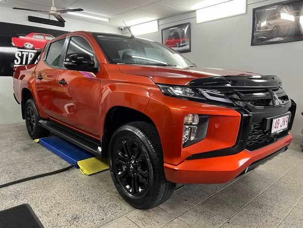 Orange Pickup Truck on A Car Lift in A Garage — Straightline Detailing Cairns in Bungalow, QLD