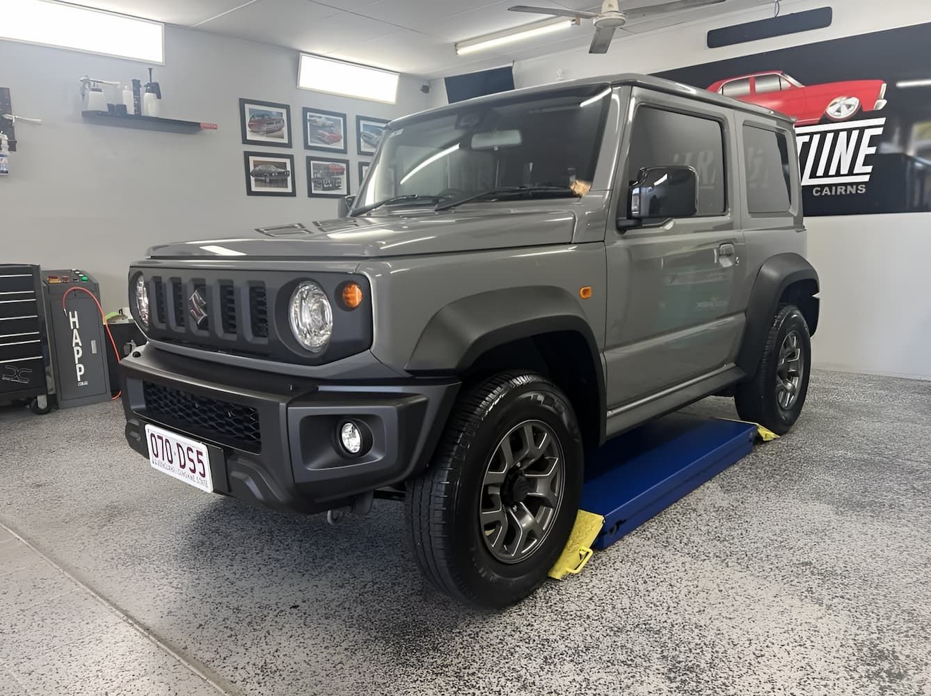 Gray Suzuki Jimny SUV On a Blue Lift in An Auto Shop Garage — Straightline Detailing Cairns in Bungalow, QLD