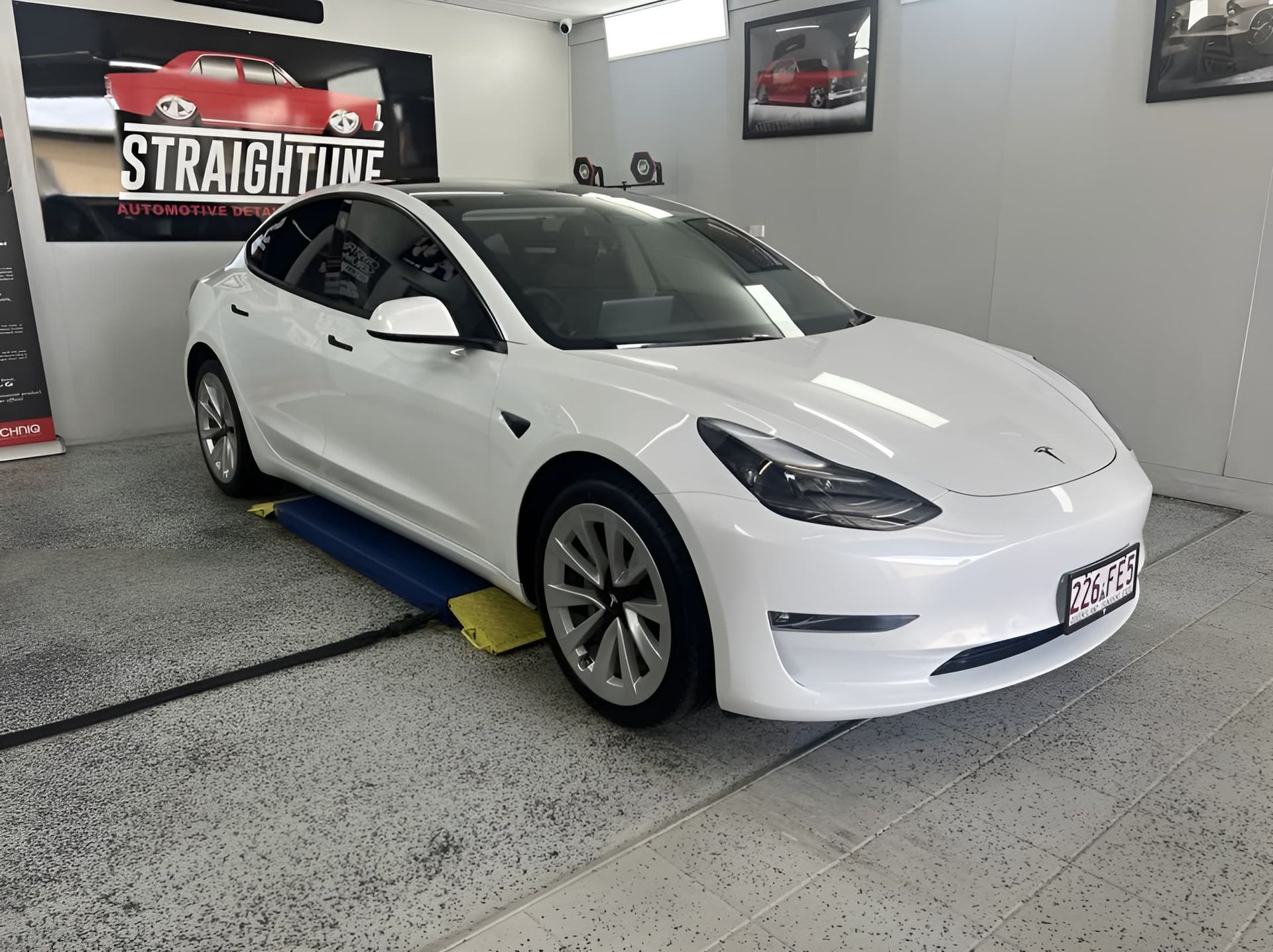 White Tesla Sedan in An Indoor Showroom — Straightline Detailing Cairns in Bungalow, QLD