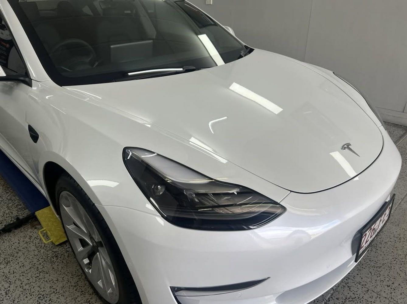 A White Tesla Model 3 is Parked in a Garage — Straightline Detailing Cairns in Bungalow, QLD