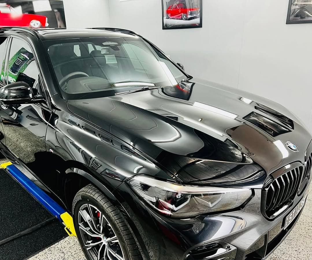A Black BMW X5 is Parked in a Garage — Straightline Detailing Cairns in Bungalow, QLD