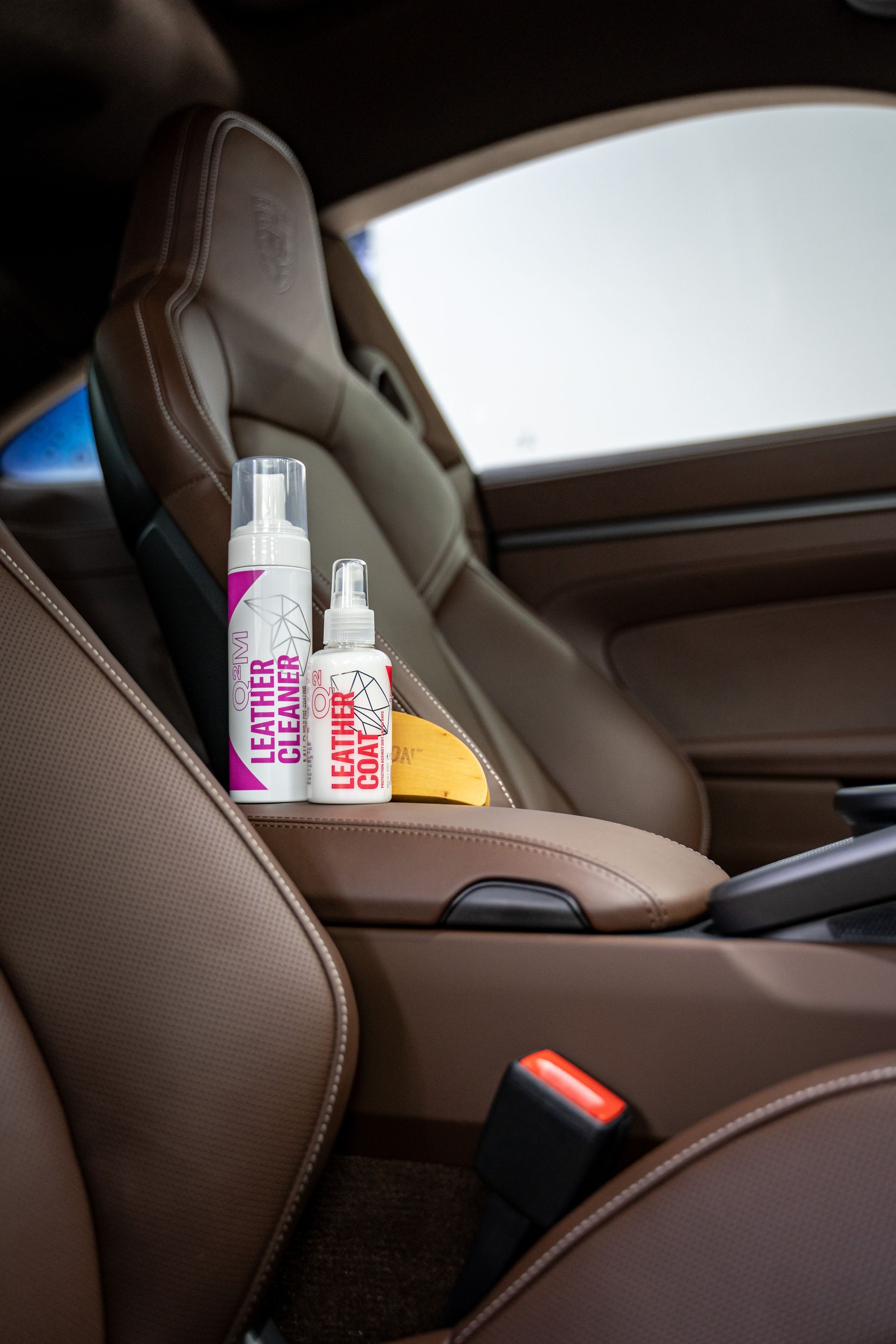Two Small Pink-And-White Bottles on A Tan Car Seat — Straightline Detailing Cairns in Bungalow, QLD