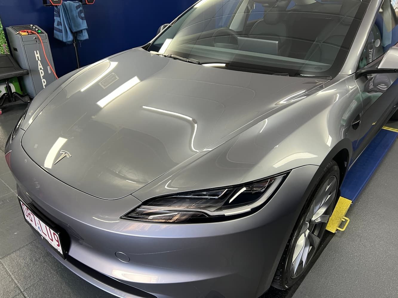 A Tesla Model 3 is Parked on a Lift in a Garage — Straightline Detailing Cairns in Bungalow, QLD