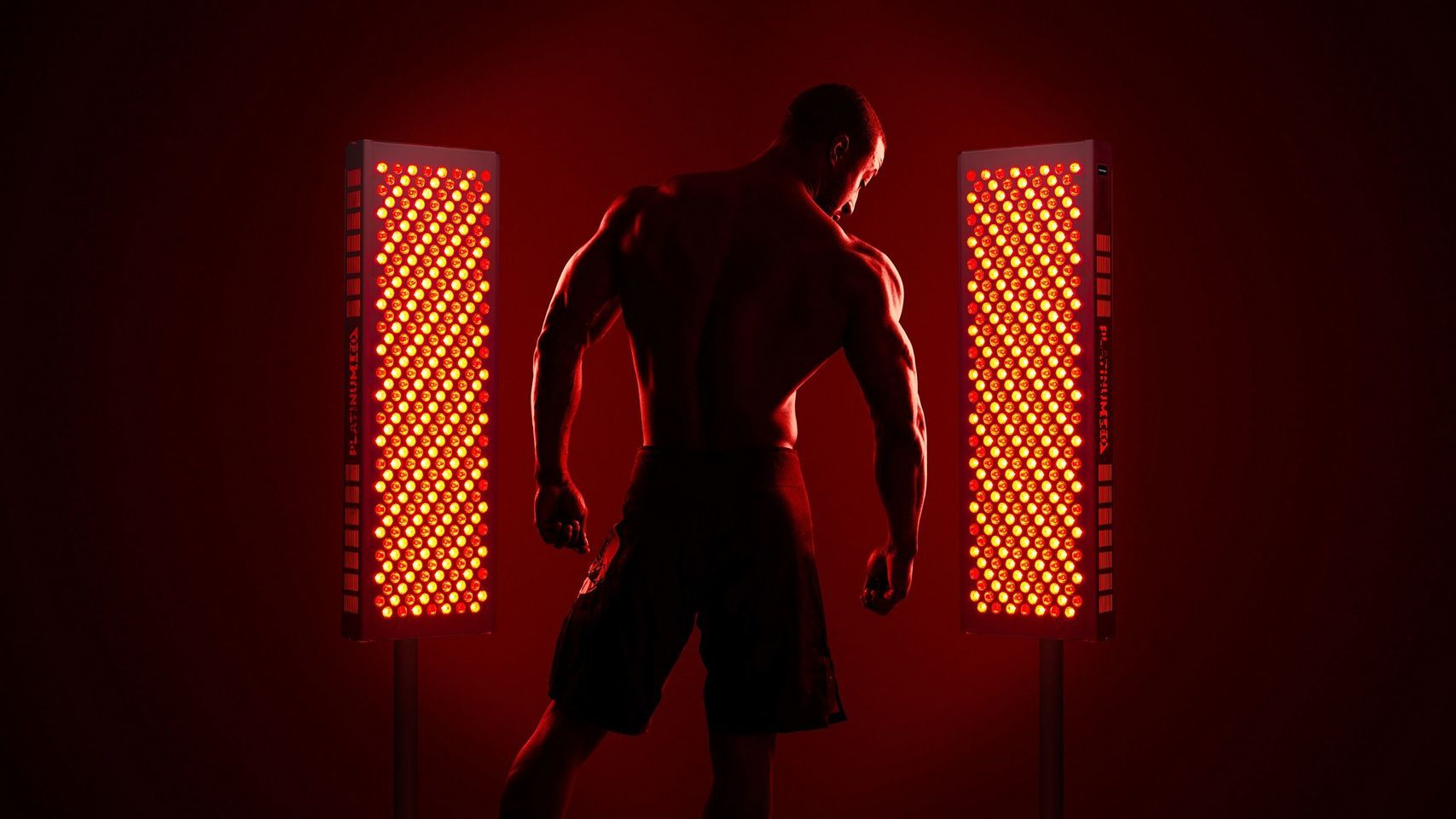A man is standing in front of two red lights in a dark room.