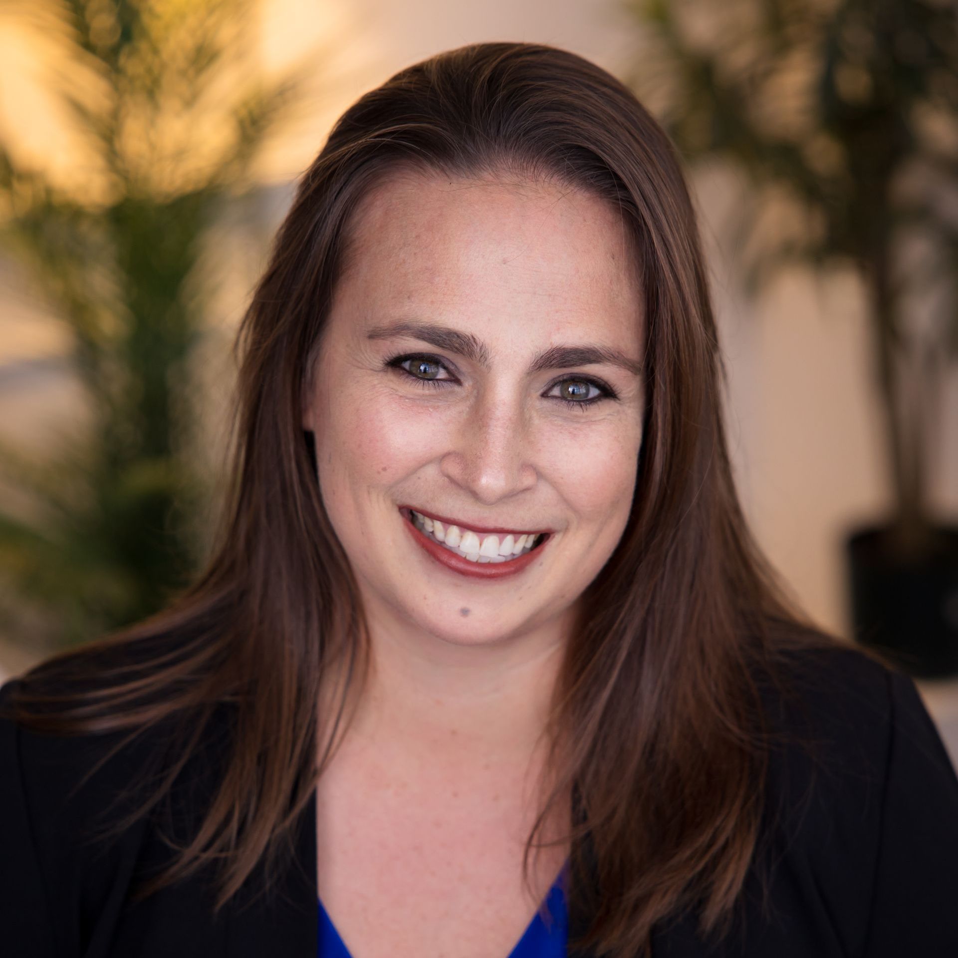 a woman in a black jacket and blue shirt is smiling for the camera .