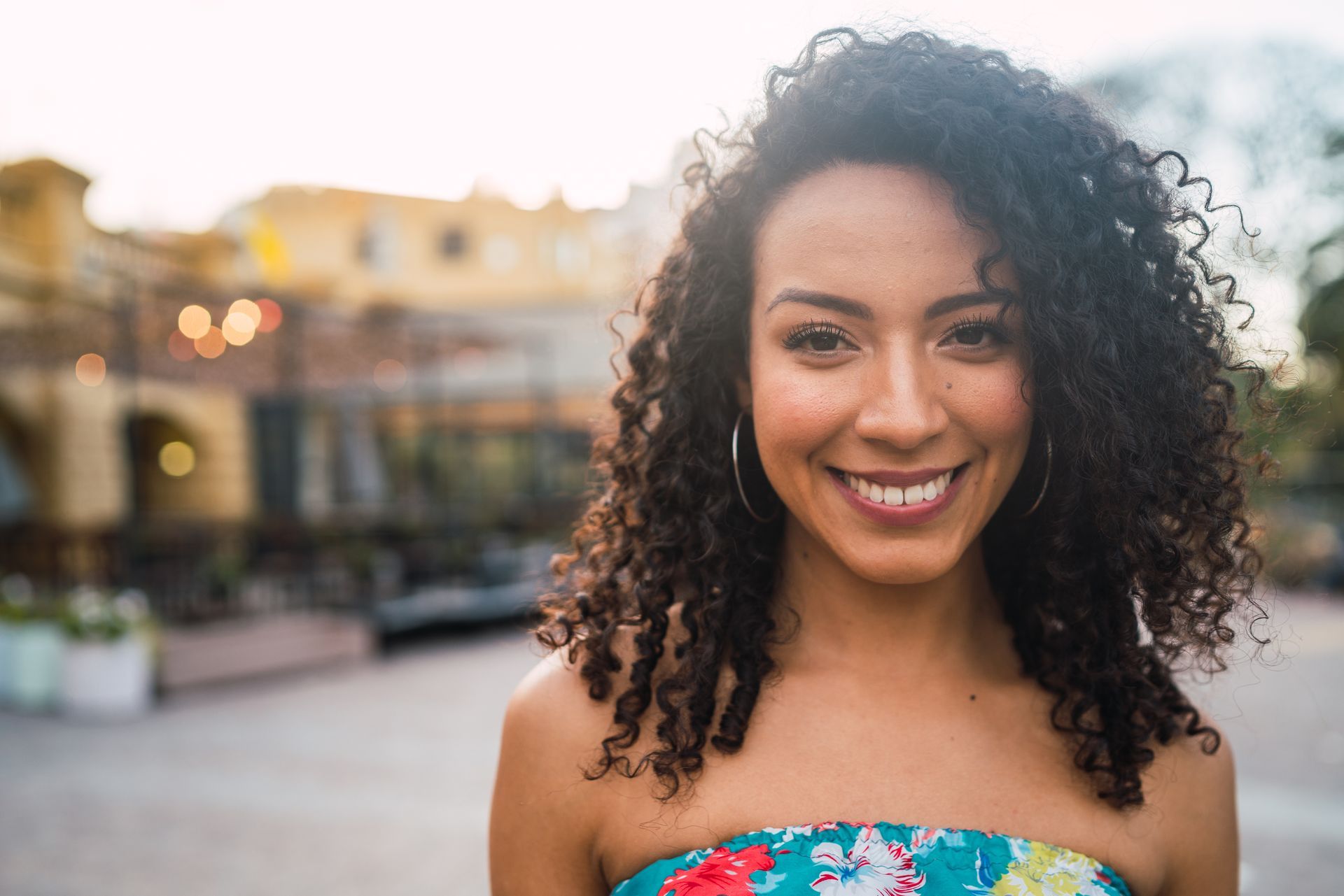 a woman with curly hair is smiling for the camera .