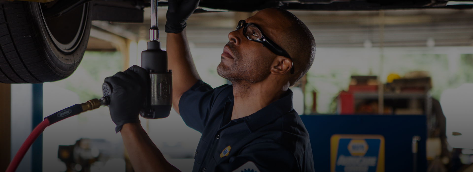Mechanic using an impact wrench under a vehicle in a garage. | Northlake Automotive
