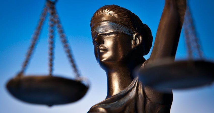 blindfolded woman holds justice scale