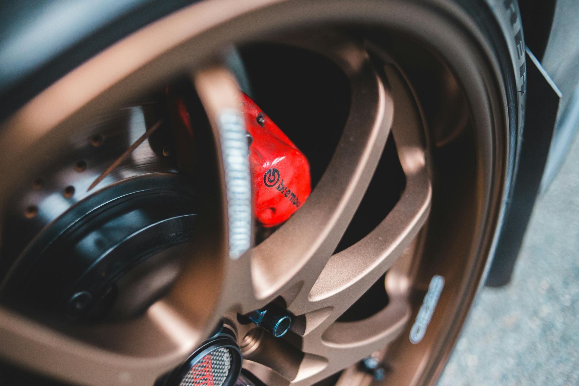 A close up of a car wheel with a red brake caliper.