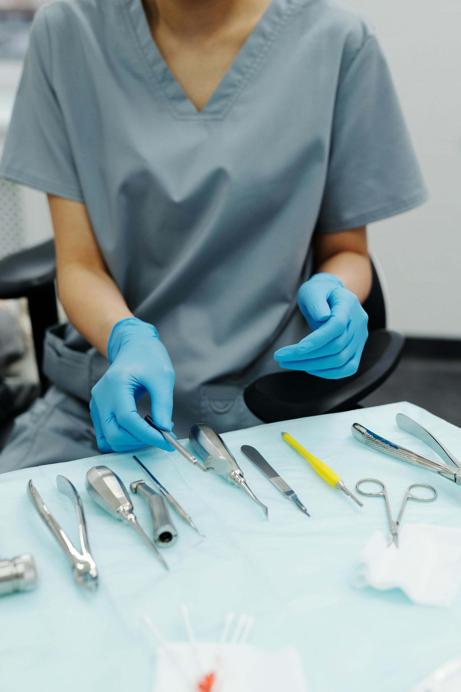 A woman is sitting at a table with dental instruments on it.