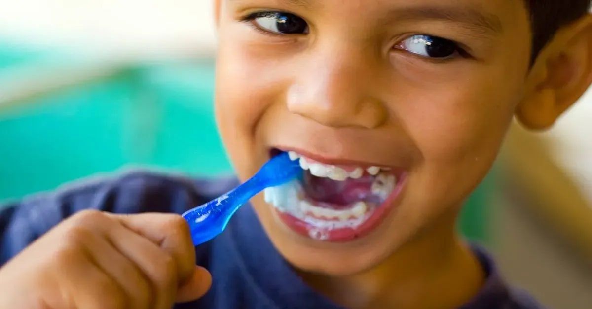 A young boy is brushing his teeth with a blue toothbrush.