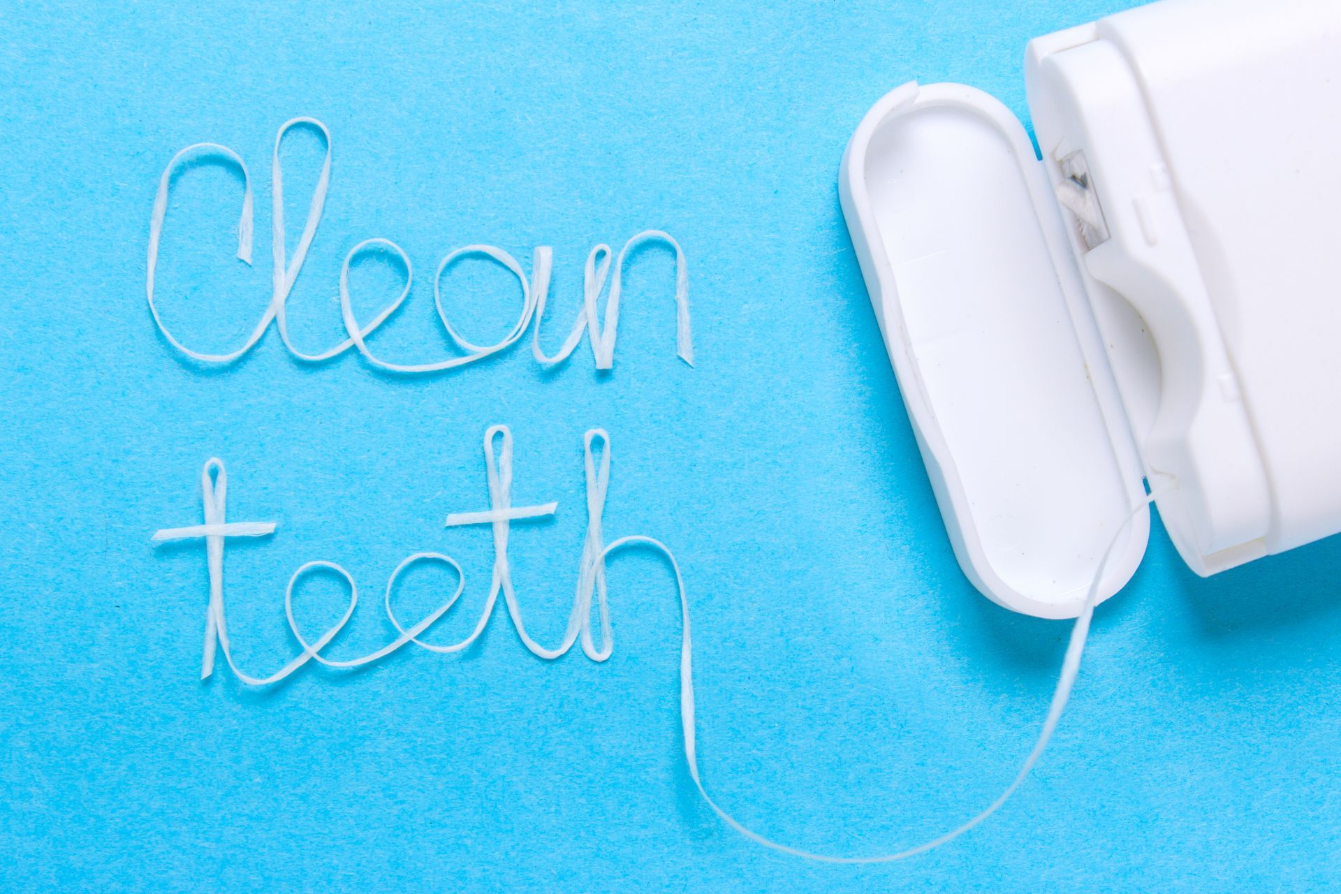 clean teeth spelled using floss thread