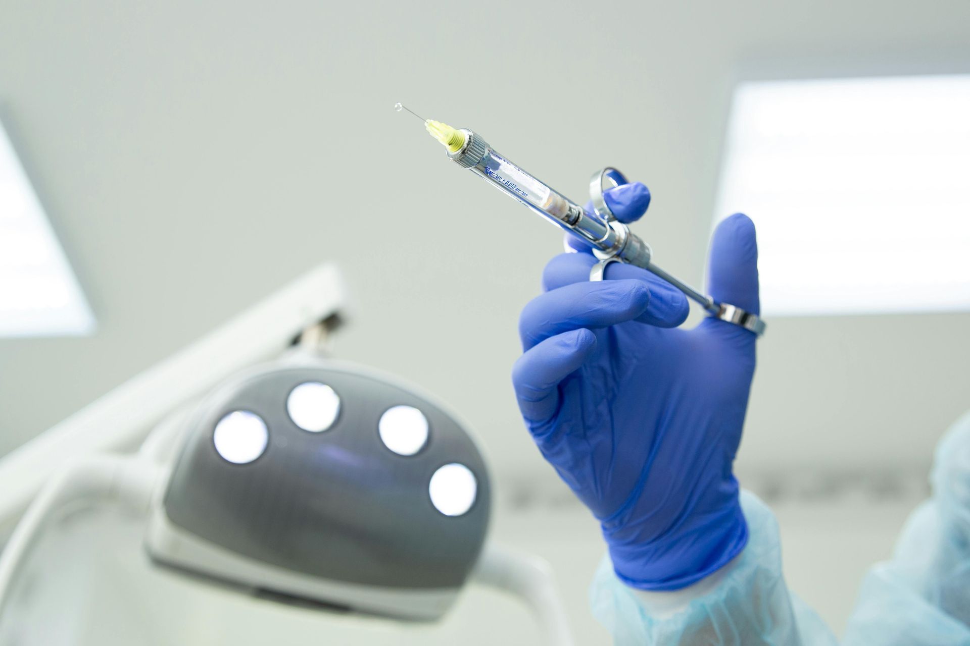 A dentist is holding a syringe in his hand in a dental office.