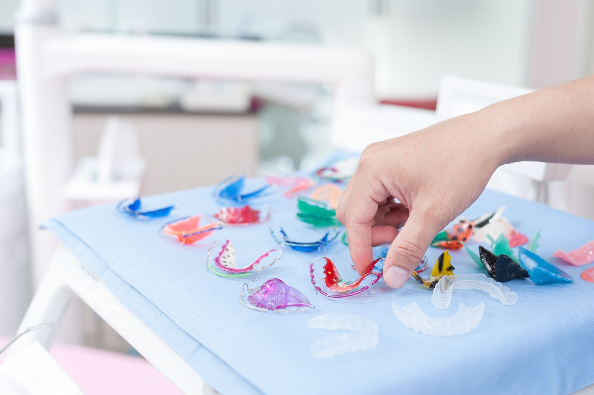 A person is reaching for a dental retainer on a table.
