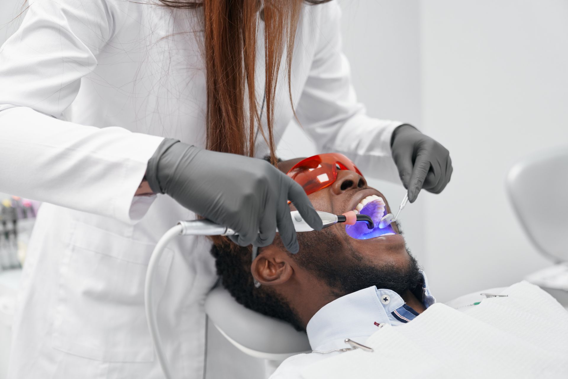A man is getting his teeth whitened by a dentist.