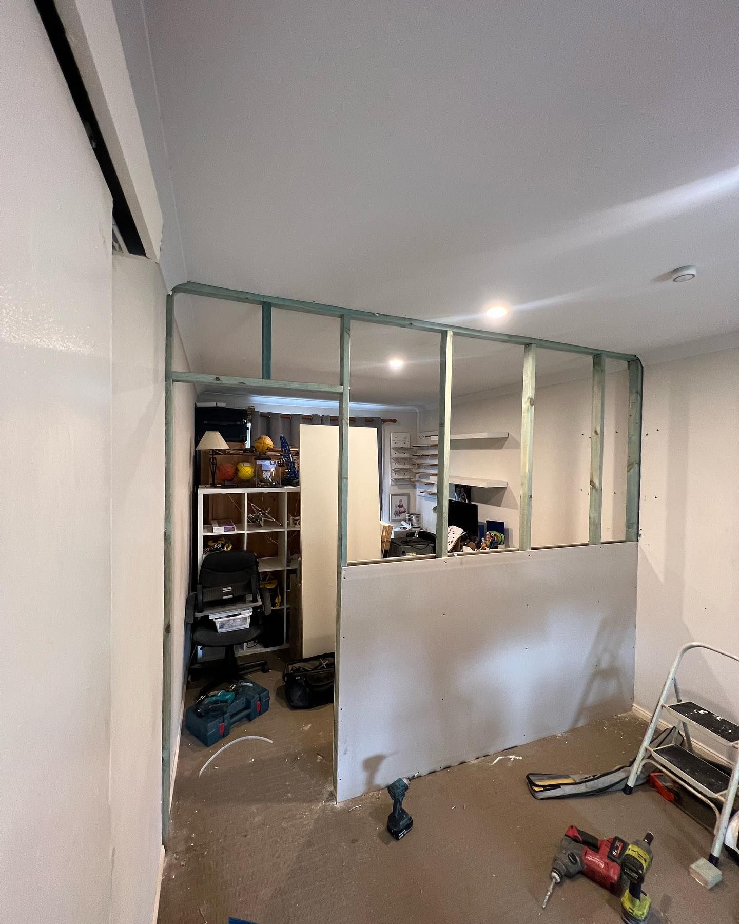 Interior view of a room under construction with exposed wooden frame and drywall.
