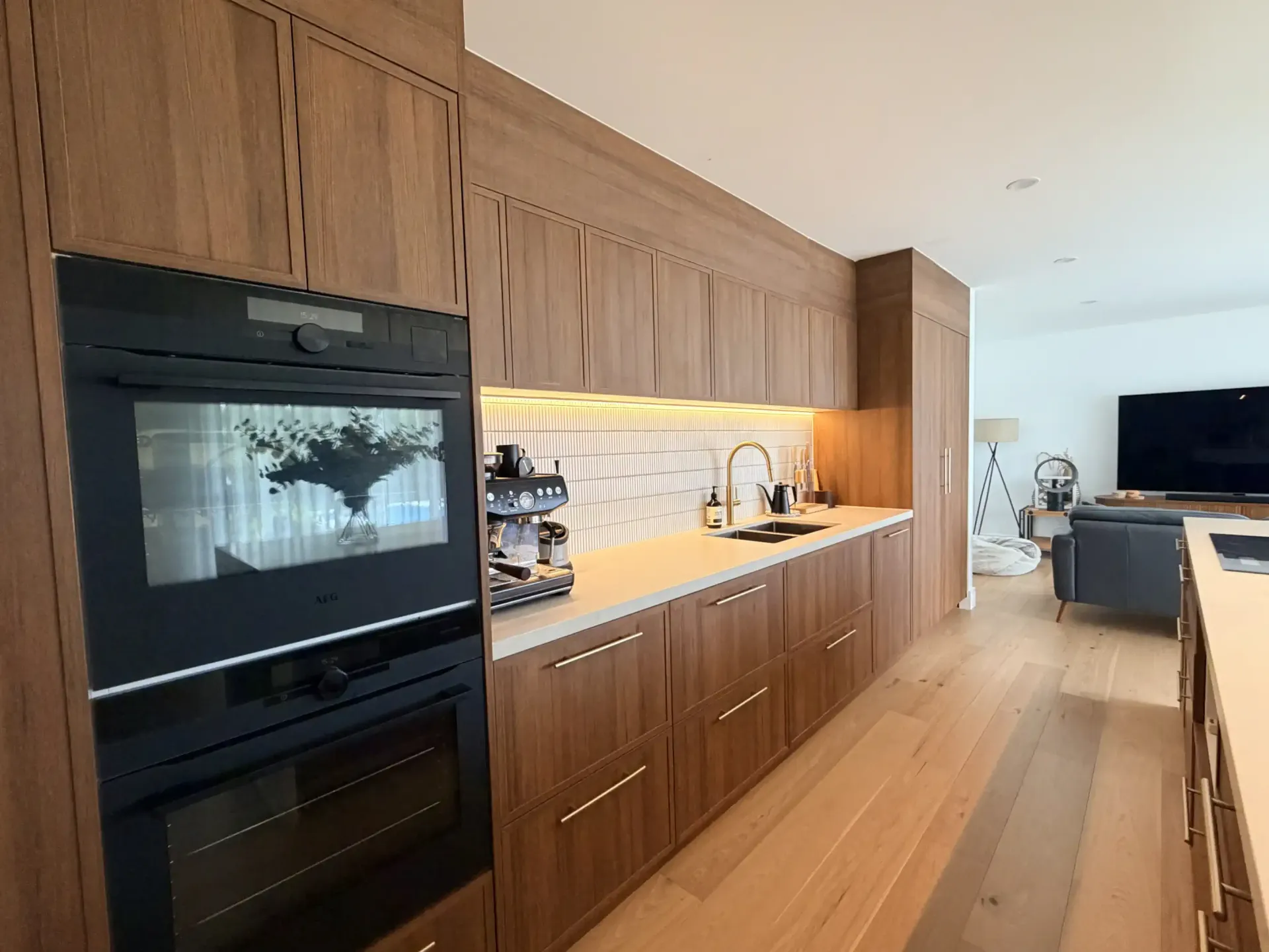 Modern white kitchen with island, cooktop, and range hood.