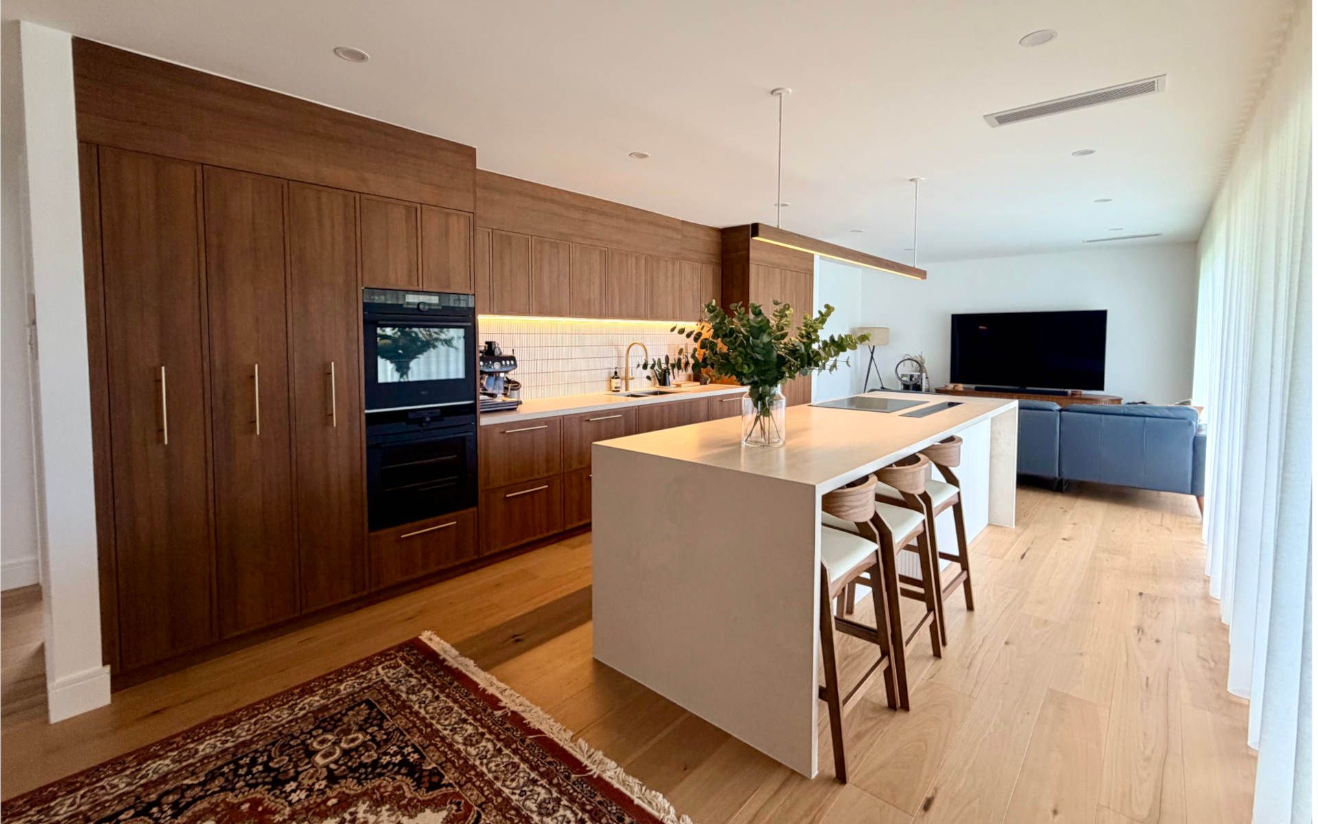 Modern kitchen with white island, light wood cabinets, and stainless steel range hood.