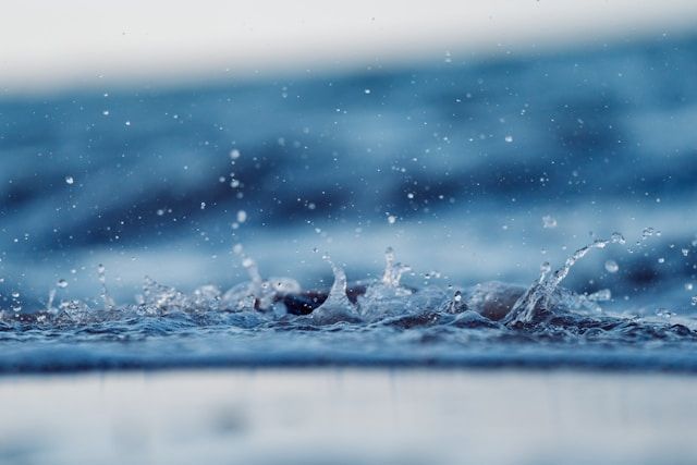 Water droplets splashing on surface with soft blue tones, symbolizing reflection, funeral homes Salt