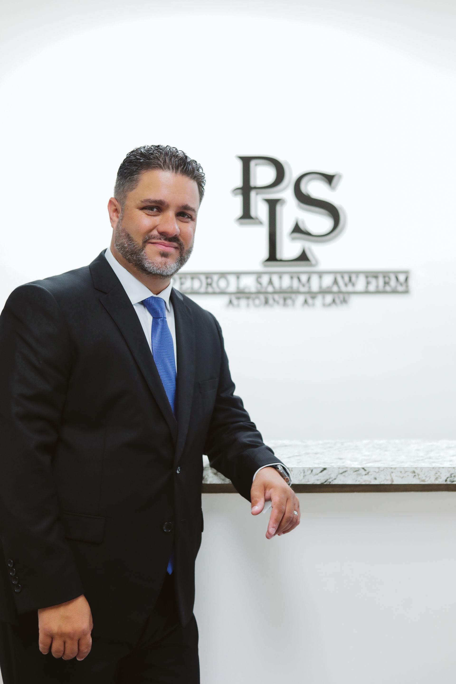 A man in a suit and tie is standing in front of a ps law firm sign.