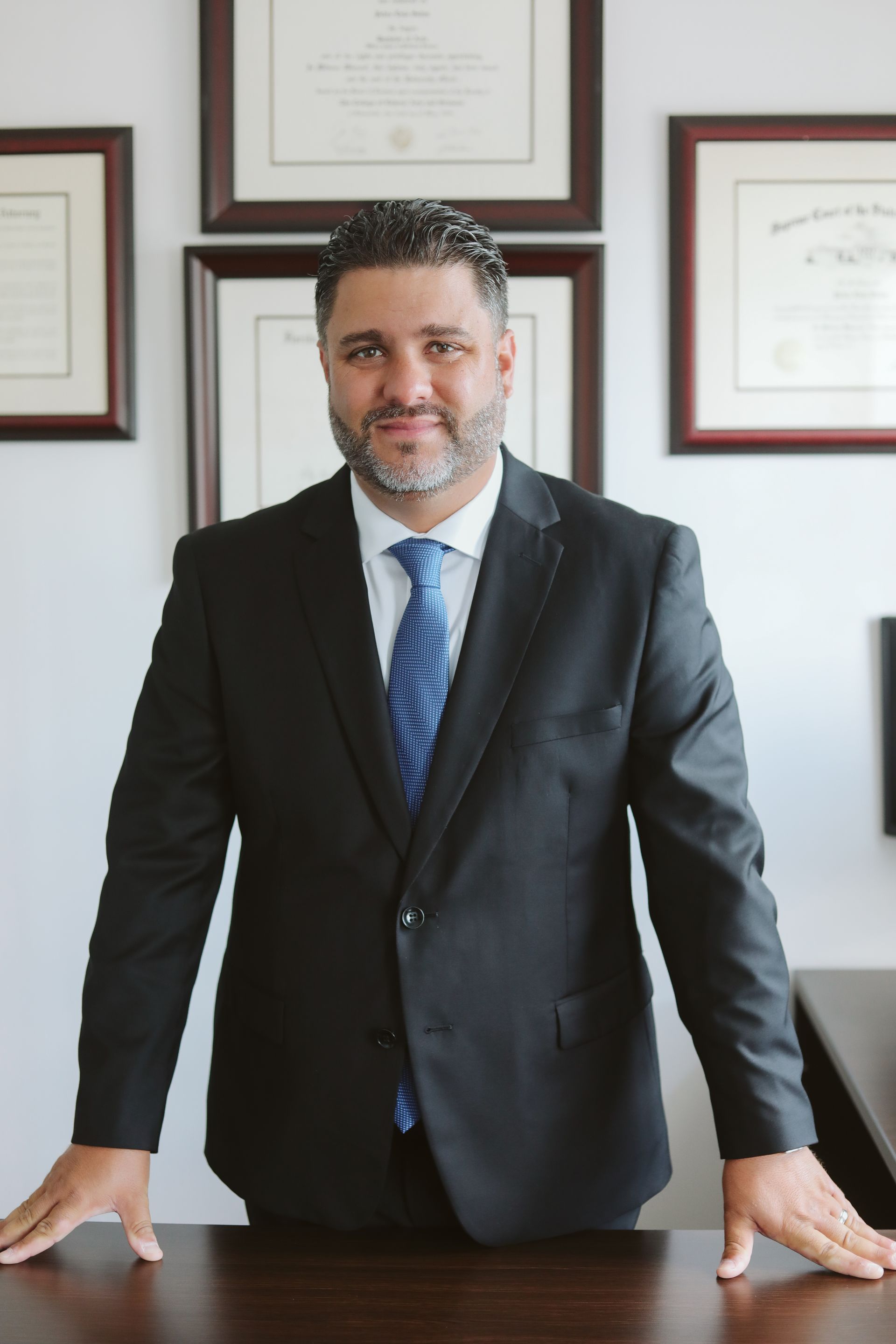 A man in a suit and tie is standing in front of a desk.