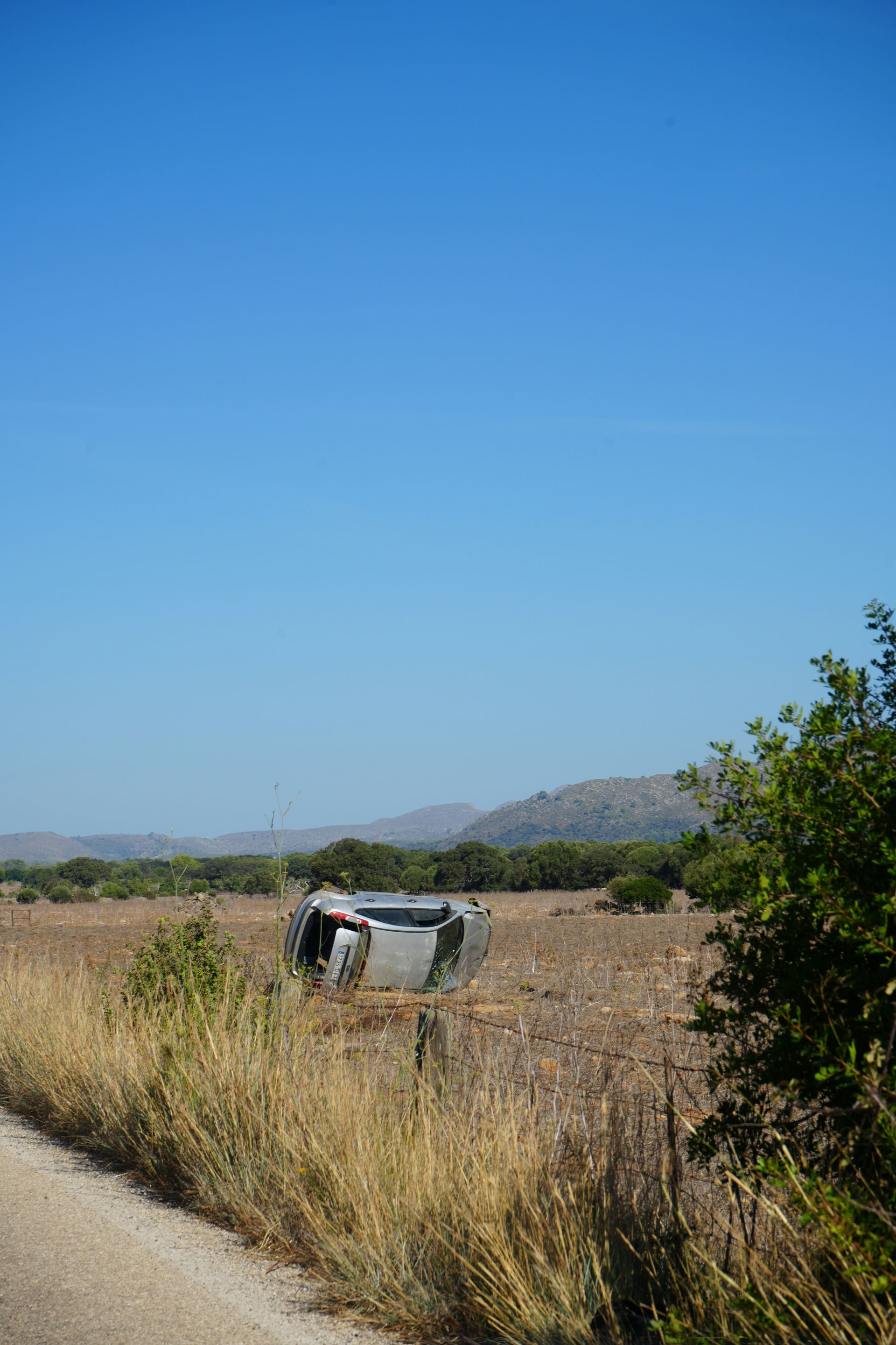 A car is on its side in the middle of a field.